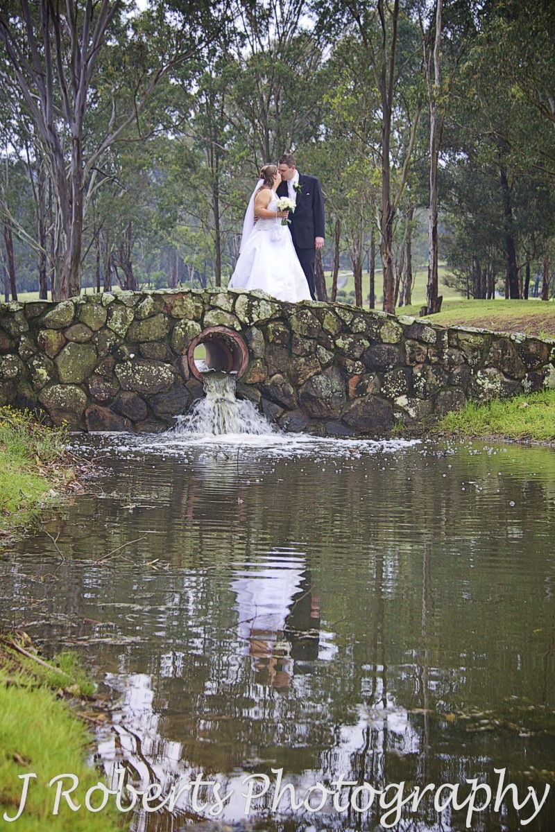 Bride and groom kissing with reflection on lake - wedding photography sydney